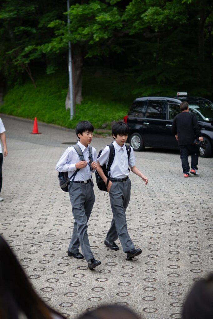 Two Japanese schoolboys in uniforms walking outdoors on a summer day in Japan.
