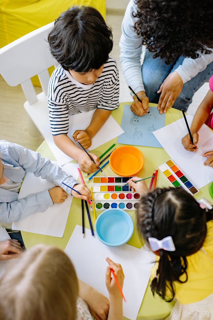 Mastering the First Impression: Your intriguing post title goes here Top view of children painting with watercolors at a preschool art class.